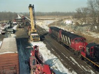 Submitted on the 24th anniversary of the Hyde Park train crash.  I recommend the TSB Report about this mishap - http://www.bst-tsb.gc.ca/eng/rapports-reports/rail/1995/r95s0021/r95s0021.asp <br> This is a non-telephoto view of the accident scene, seen from the Hyde Park Road overpass. It could be the day of the crash, or a day or more later. A westbound train is proceeding forward from the bottom right on the now-clear north track, with lead unit CN9470, CN9516, CN7213.<br> Accident cleanup must have been aided by the level ground, available siding track, and good road access at the western fringe of London ON.  Three cranes are on scene and two backhoes are visible, with men at work on the damaged south track.  Derailed HR616 CN 2105, lead unit on train 272, remains where it landed - it originally faced eastward toward the vantage point. Mangled railcars have been hauled away from the tracks. A pile of light coloured material, between the spur track and the north main, is thought to be from a hopper car destroyed in the crash. Train 272's damaged trailing unit LMSX 723 had been re-railed and moved to the siding  (still tail-end first), along with a boxcar damaged in the crash. The facing train of autoracks looks like the main part of train 272, in which case rescue locomotives are on the front of it.  <br>You can click on "Photographer" for a couple of other views, including prior-to-cleanup <a href=http://www.railpictures.ca/?attachment_id=36332><b>image 36332</b></a>.